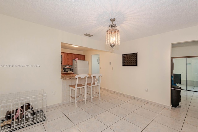 interior space featuring light tile patterned floors, a chandelier, and a textured ceiling