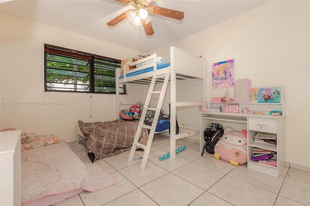 bedroom with ceiling fan, light tile patterned flooring, and a textured ceiling