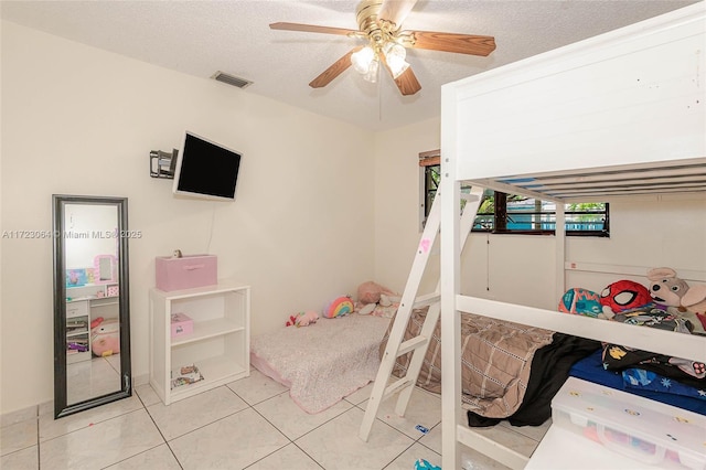 tiled bedroom with ceiling fan and a textured ceiling