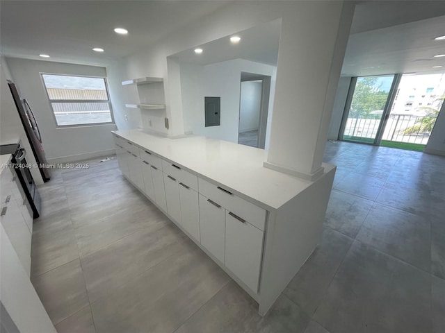 kitchen featuring a wealth of natural light, white cabinetry, electric panel, and fridge