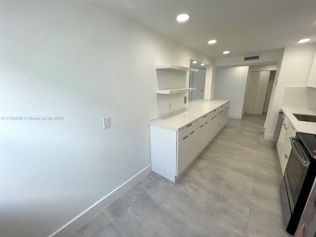 kitchen with electric range and white cabinetry