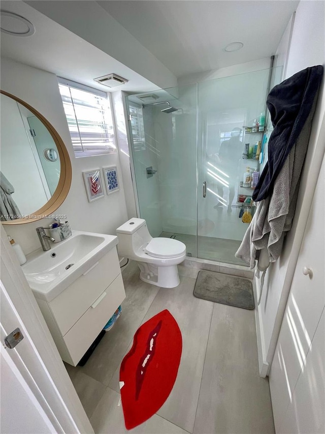 bathroom with tile patterned flooring, vanity, toilet, and a shower with door