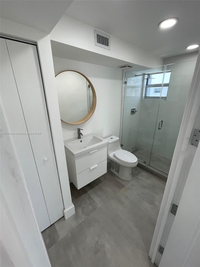 bathroom featuring vanity, toilet, and a shower with shower door