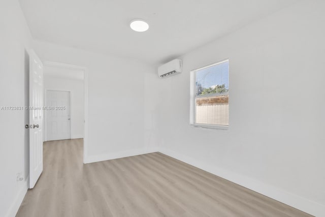 unfurnished room with an AC wall unit and light wood-type flooring