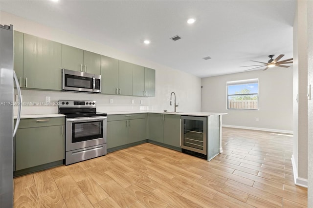 kitchen featuring kitchen peninsula, appliances with stainless steel finishes, ceiling fan, green cabinetry, and wine cooler