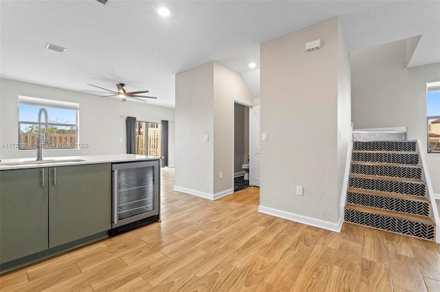 kitchen with ceiling fan, sink, beverage cooler, light hardwood / wood-style floors, and green cabinetry