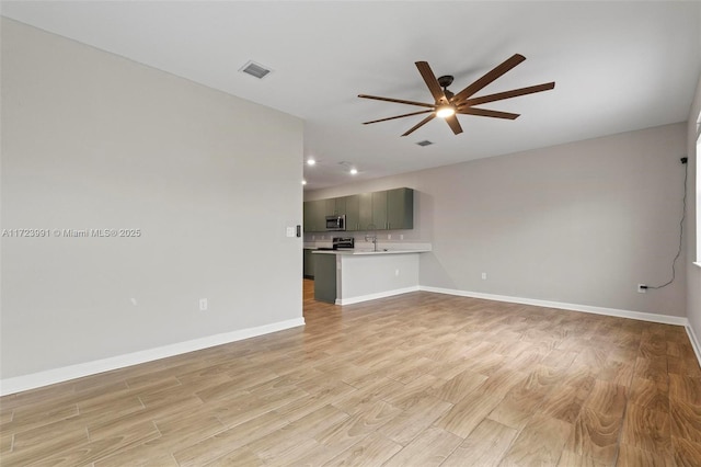 unfurnished living room featuring ceiling fan, light wood-type flooring, and sink