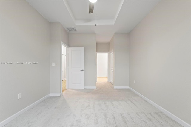 carpeted empty room featuring a tray ceiling and ceiling fan