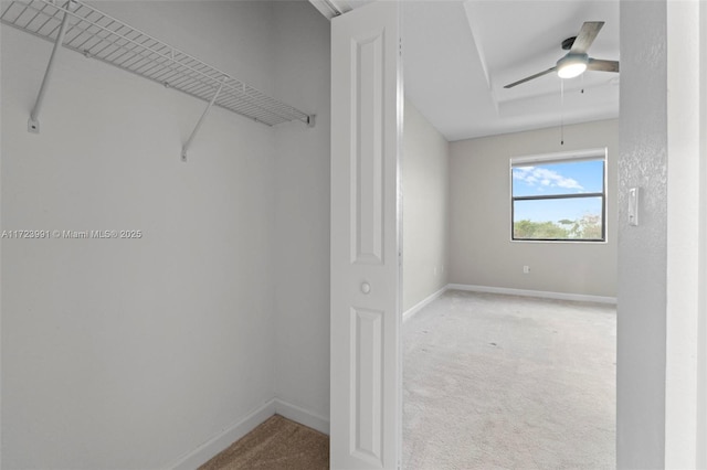 walk in closet with ceiling fan and light colored carpet