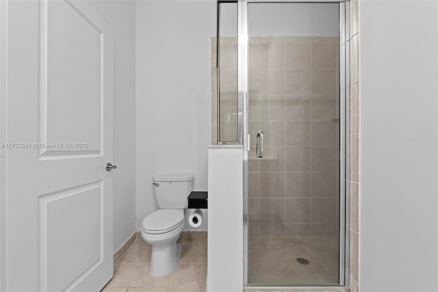 bathroom featuring tile patterned floors, a shower with door, and toilet