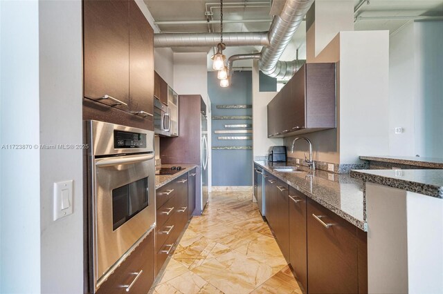 kitchen featuring appliances with stainless steel finishes, sink, dark brown cabinetry, and dark stone countertops