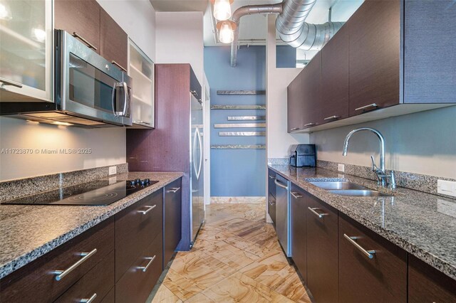 kitchen featuring dark stone countertops, dark brown cabinetry, sink, and appliances with stainless steel finishes