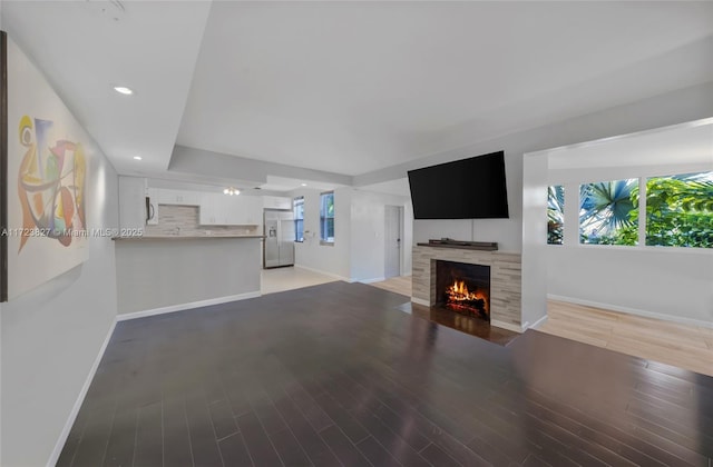 unfurnished living room with a tile fireplace, baseboards, light wood-style floors, and recessed lighting