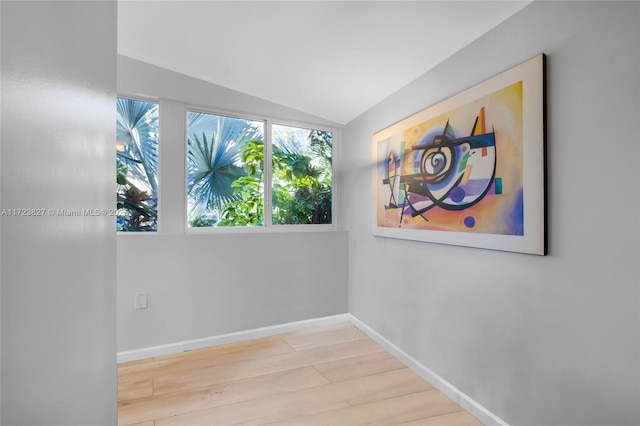 spare room with baseboards, lofted ceiling, and wood finished floors