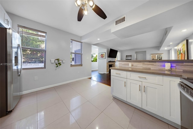 kitchen with white cabinets, ceiling fan, dark stone countertops, light tile patterned flooring, and stainless steel fridge with ice dispenser