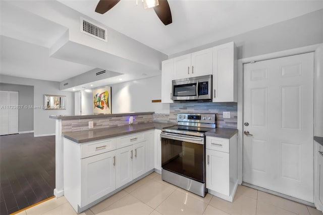 kitchen with visible vents, dark countertops, ceiling fan, a peninsula, and appliances with stainless steel finishes