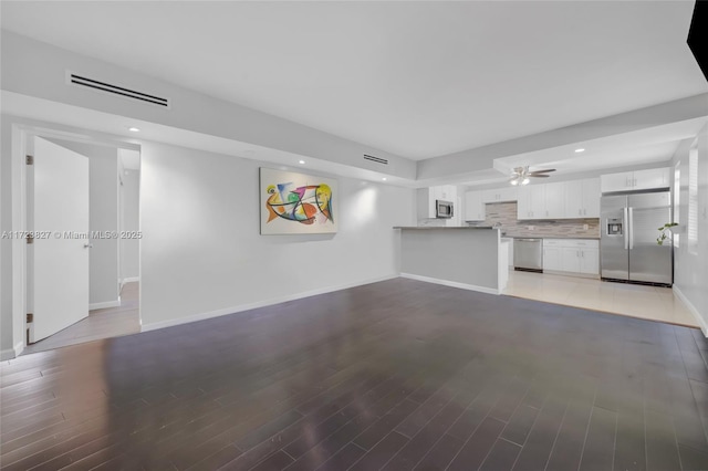 unfurnished living room featuring dark hardwood / wood-style flooring and ceiling fan