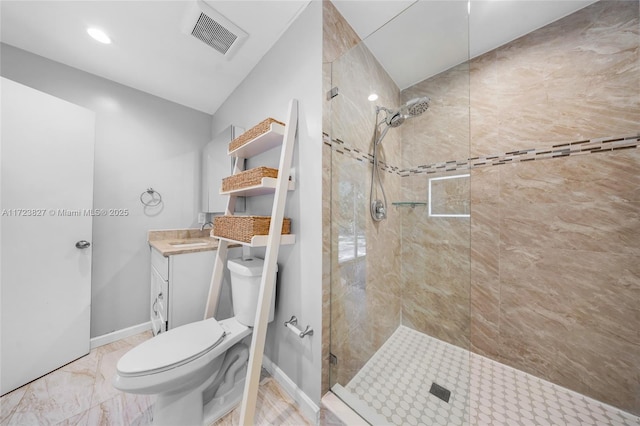 bathroom with a tile shower, vanity, and toilet