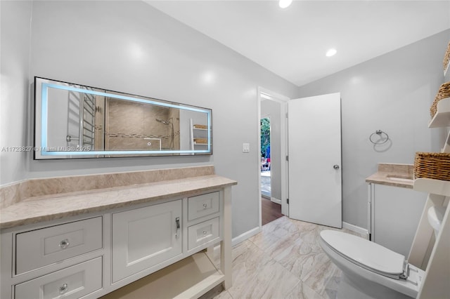 bathroom with baseboards, marble finish floor, toilet, tiled shower, and vanity