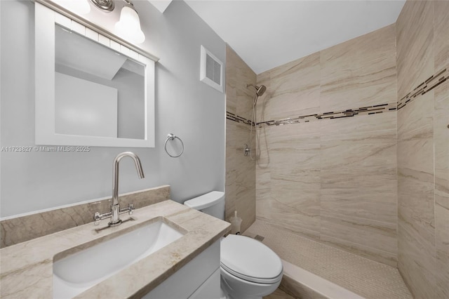 bathroom featuring vanity, visible vents, toilet, and tiled shower