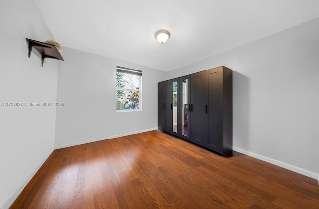 unfurnished bedroom featuring access to exterior, baseboards, and wood finished floors
