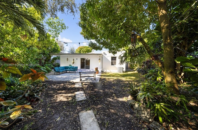 rear view of property featuring stucco siding, an outdoor living space, and a patio