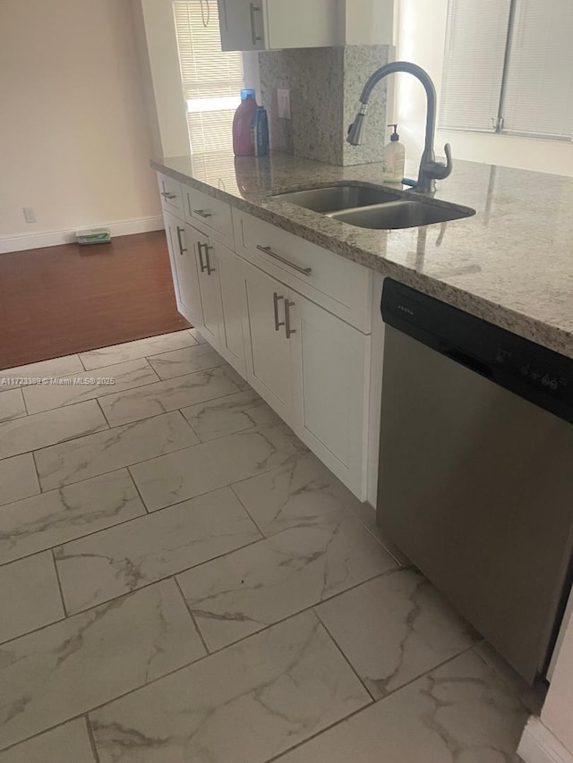 kitchen with light stone countertops, backsplash, stainless steel dishwasher, sink, and white cabinets