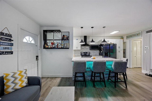 kitchen featuring stainless steel appliances, white cabinets, island exhaust hood, a breakfast bar area, and pendant lighting