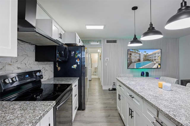 kitchen featuring white cabinets, wall chimney range hood, black appliances, and light stone countertops