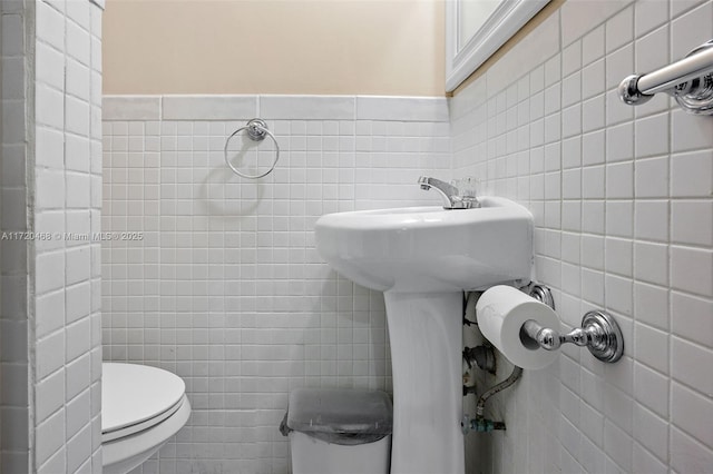 bathroom featuring toilet and tile walls