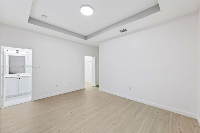 unfurnished room featuring a raised ceiling and light wood-type flooring