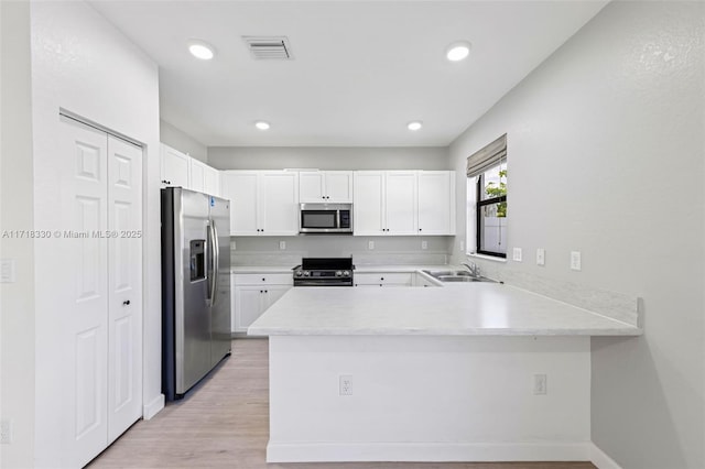 kitchen with white cabinets, sink, kitchen peninsula, and stainless steel appliances