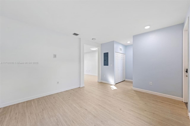 empty room with electric panel and light wood-type flooring