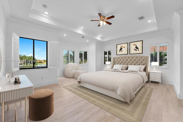 bedroom featuring a raised ceiling, light wood-type flooring, and multiple windows