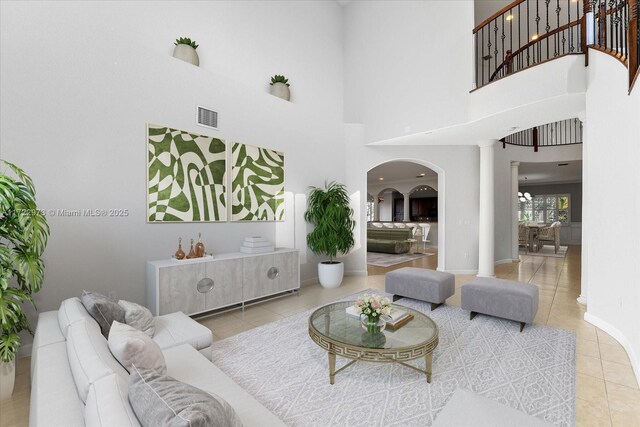 living room with tile patterned flooring, a towering ceiling, and decorative columns