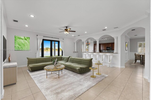 living room featuring crown molding, plenty of natural light, light tile patterned flooring, and ceiling fan