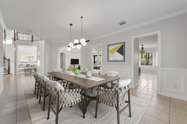 tiled dining area with plenty of natural light, an inviting chandelier, and ornamental molding