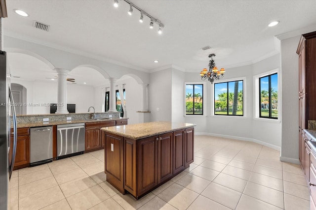 kitchen featuring decorative light fixtures, sink, a center island, light stone counters, and stainless steel appliances