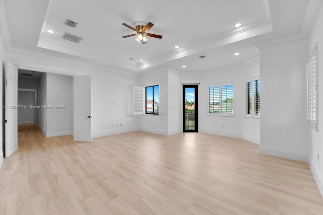 unfurnished bedroom with light wood-type flooring, a tray ceiling, ceiling fan, and ornamental molding