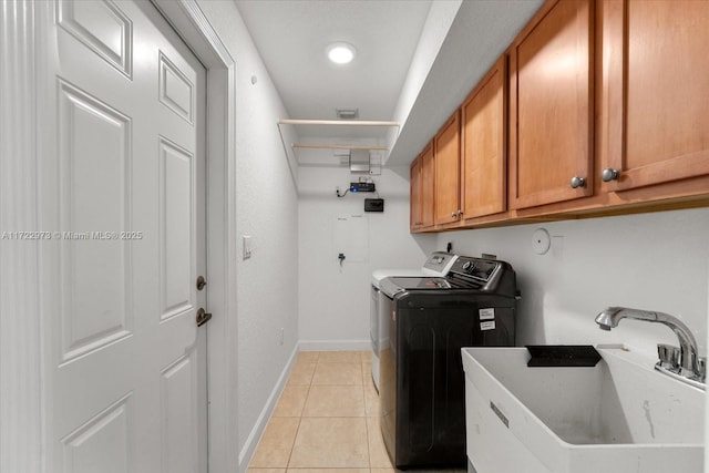 laundry area featuring washer and dryer, sink, light tile patterned floors, and cabinets