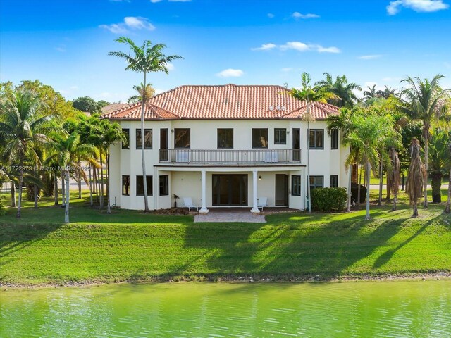 back of house with a yard, a water view, and a balcony