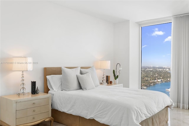 bedroom with floor to ceiling windows and a water view