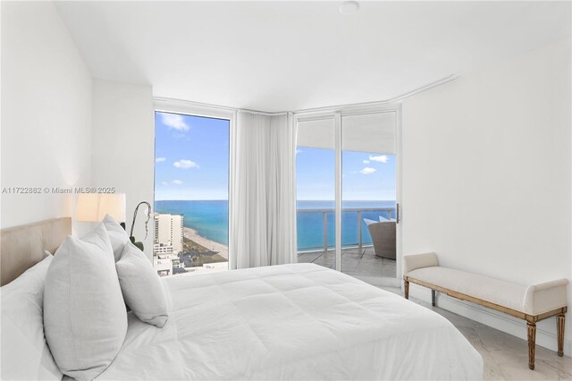 bedroom featuring access to exterior, a water view, and a wall of windows