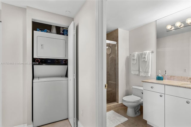 bathroom with vanity, stacked washer and clothes dryer, tile patterned floors, toilet, and a shower with shower door