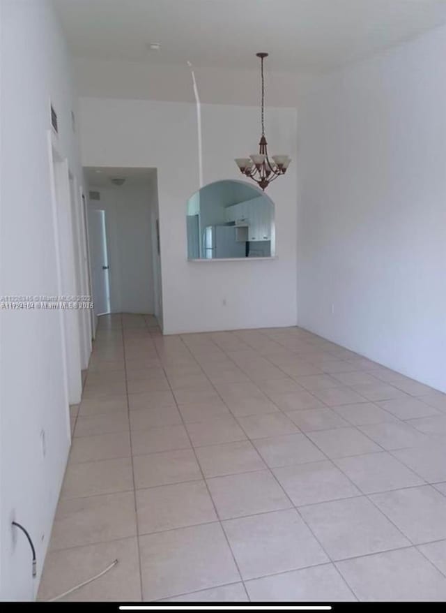 spare room featuring a chandelier and light tile patterned flooring