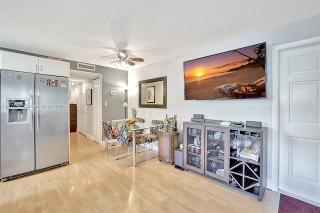 kitchen featuring light wood-type flooring, ceiling fan, stainless steel refrigerator with ice dispenser, and white cabinetry