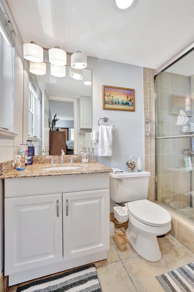 bathroom featuring a textured ceiling, walk in shower, vanity, and toilet