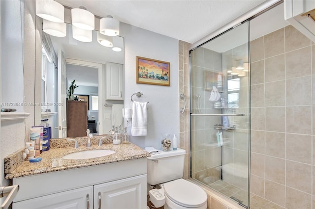 bathroom featuring a shower with door, vanity, and toilet