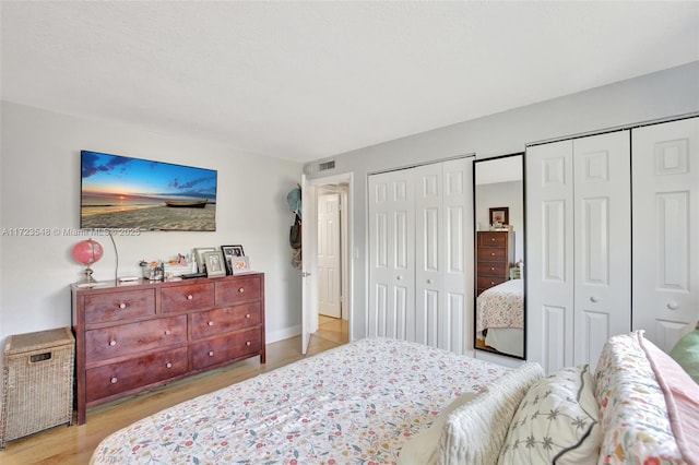 bedroom featuring two closets and light hardwood / wood-style floors