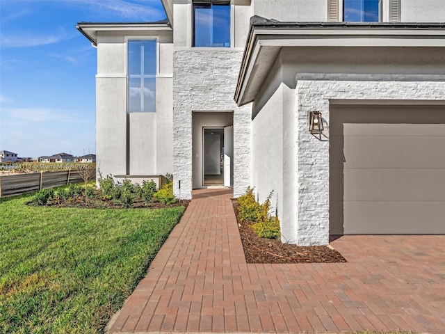 view of exterior entry with a garage and a lawn